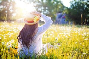 woman with arms outstretched sitting in a field