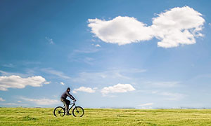 man riding bicycle across field