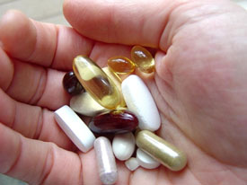 vitamin and supplement pills in palm of person's hand