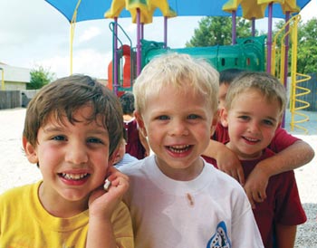 three smiling boys on a playground