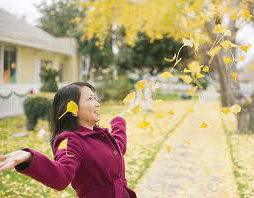 woman under falling autumn leaves