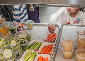 young girl choosing carrots in the school cafeteria