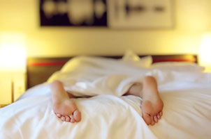 lighted bedroom showing feet sticking out of bedsheets